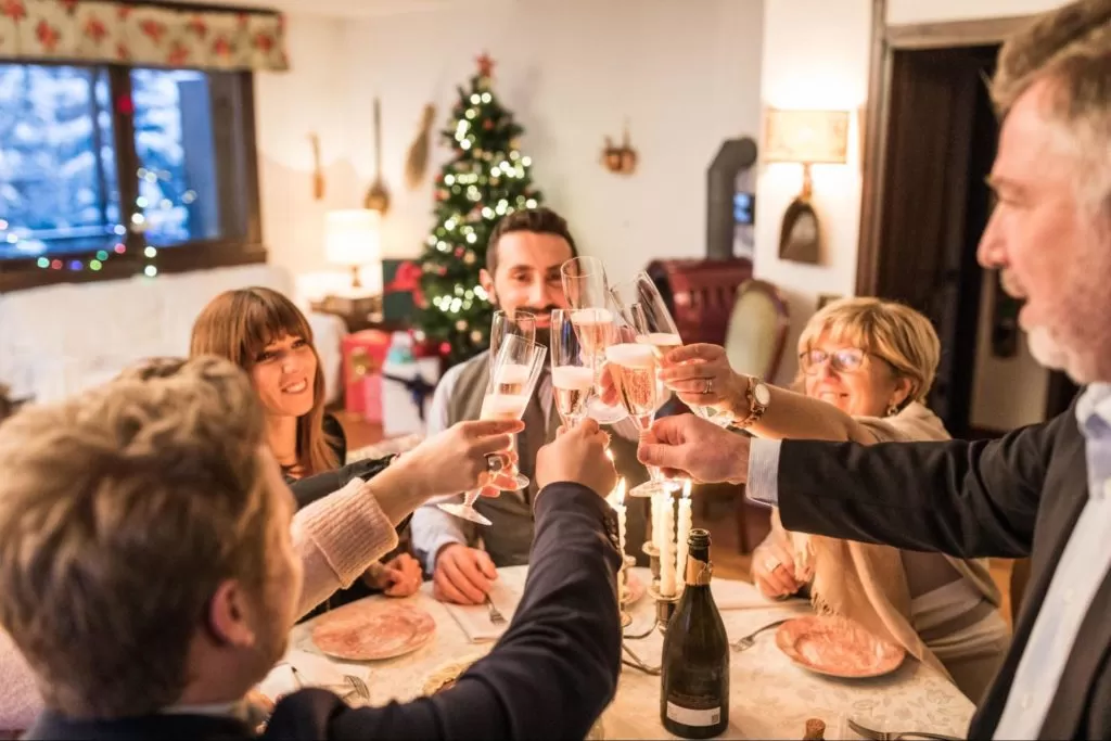 A imagem mostra pessoas reunidas à mesa celebrando uma ceia de ano novo simples e barata