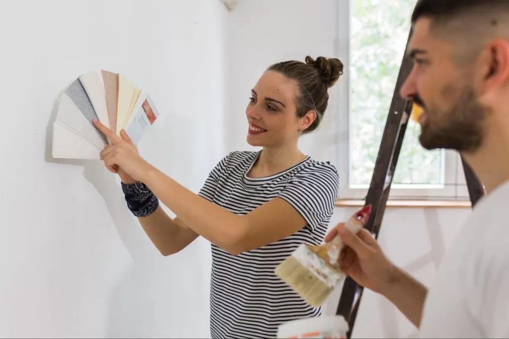 A imagem ilustra um casal escolhendo uma paleta de cores para a sua pintura geométrica.
