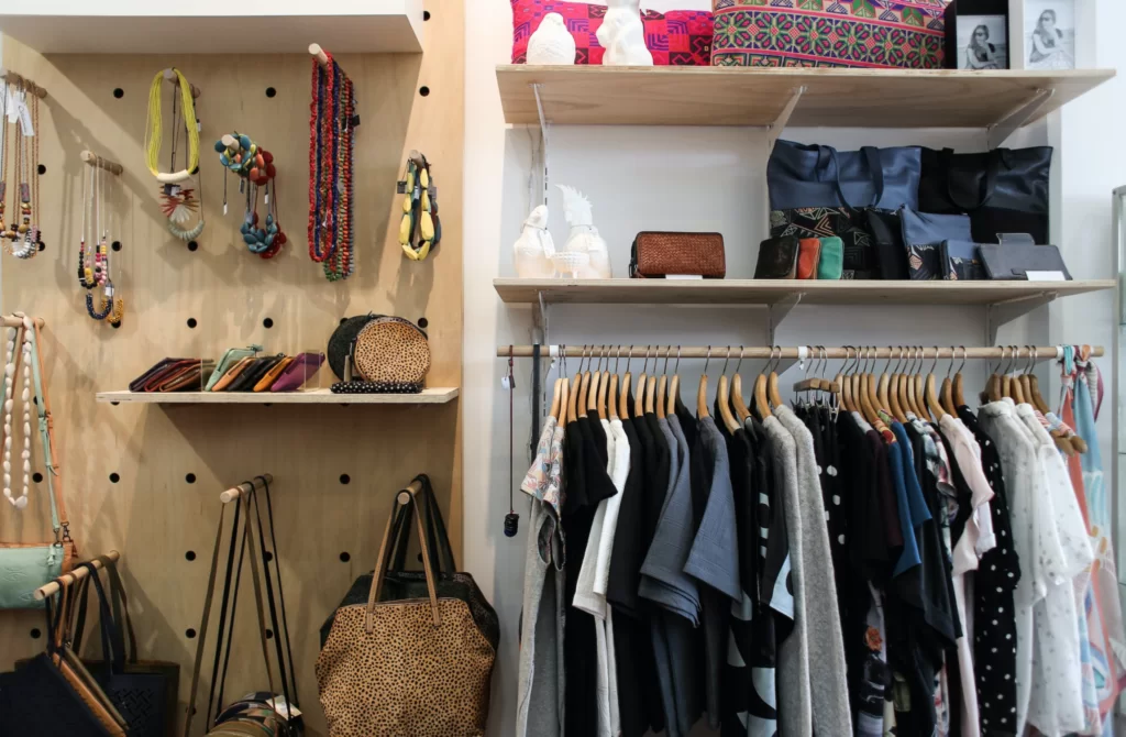 A imagem ilustra um quarto com closet pequeno repleto de roupas, acessórios coloridos e penduradores.