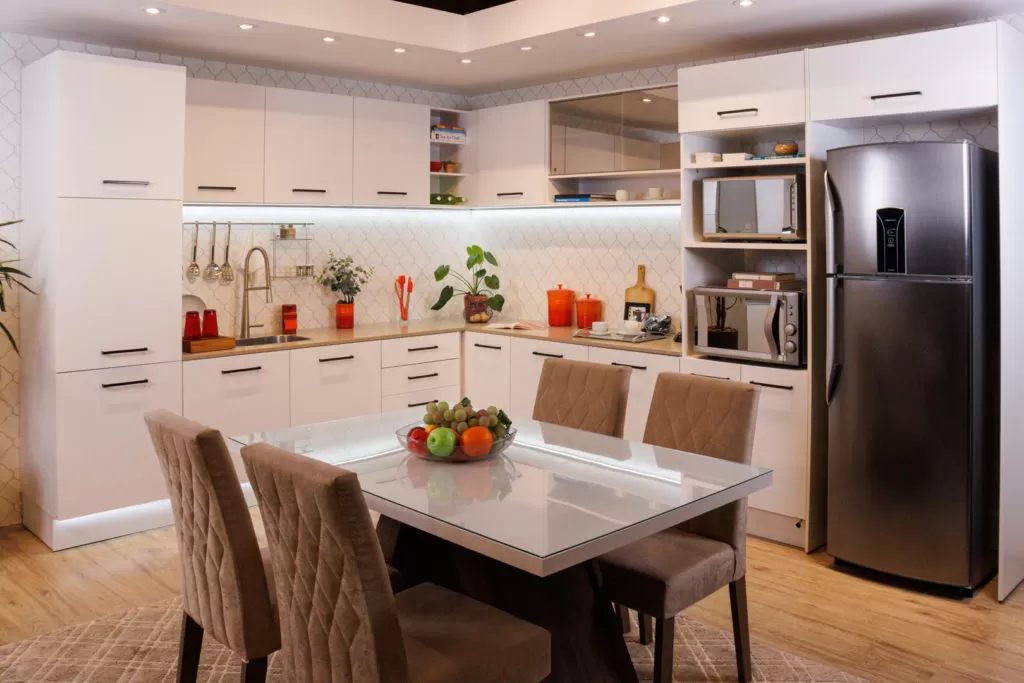 Cozinha Ágata Madesa na cor branca, com decoração e uma mesa de jantar ao centro.