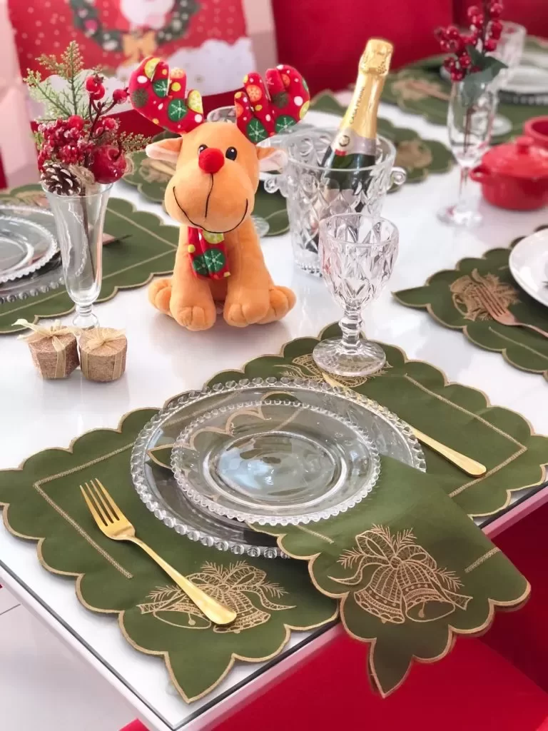 Mesa posta de Natal, decorada com guardanapos verdes e decorações com detalhes em vermelho.