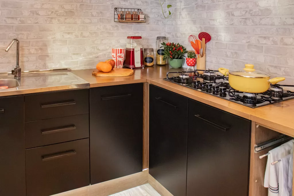 Bancada da cozinha Agata, nas cores preto e rustic, decorada com louças, vasos e outros utensílios coloridos.
