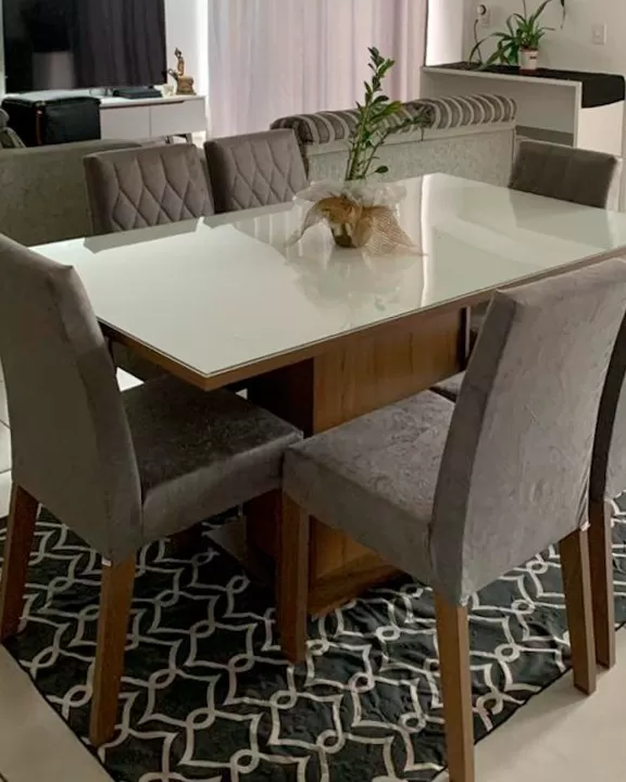 Sala de jantar e estar integradas, com mesa de jantar Geórgia Madesa nas cores cinza e rustic, decorada com uma planta e um tapete estampado.