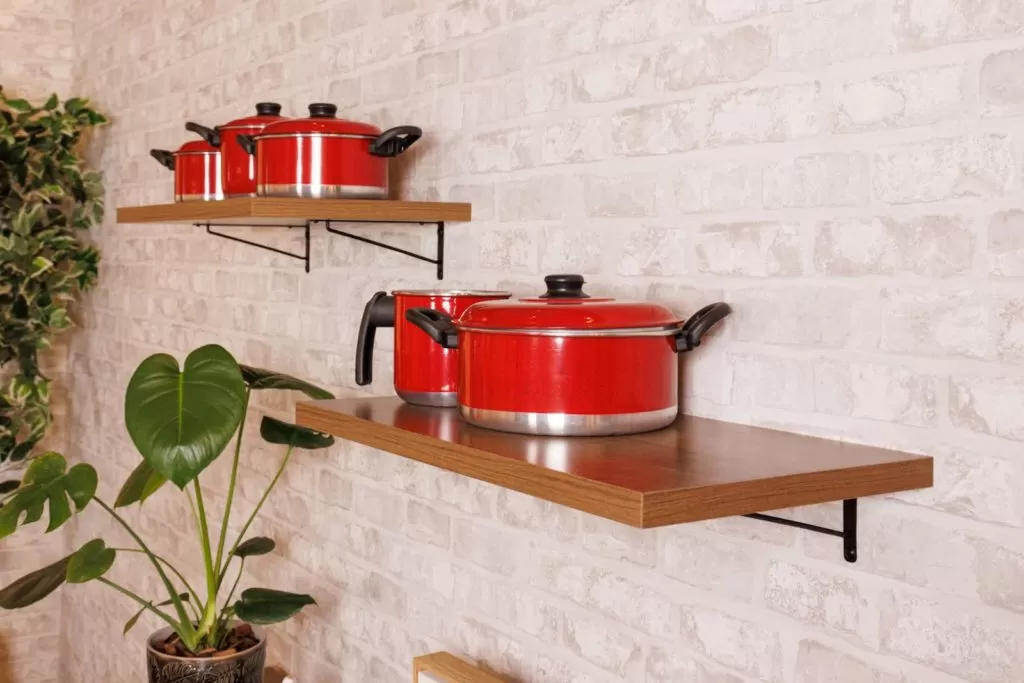 Prateleiras Madesa, decoradas com um conjunto de panelas vermelho.