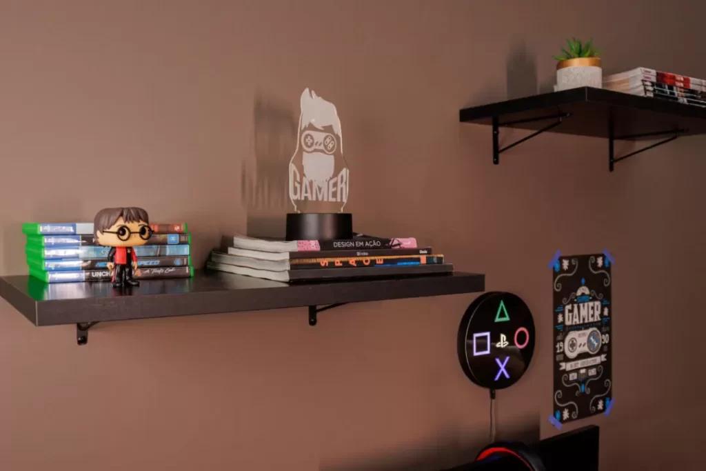 Prateleiras Madesa, na cor preta, decoradas com livros, jogos, bonecos e outros itens geek.