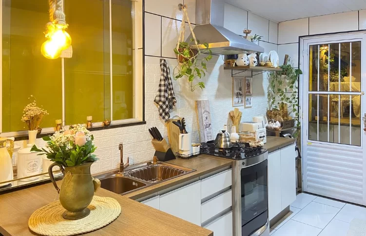 : A cozinha de uma cliente Madesa conta com elementos naturais para sua decoração, como plantas em vasos sobre prateleiras e flores sobre a mesa de madeira.