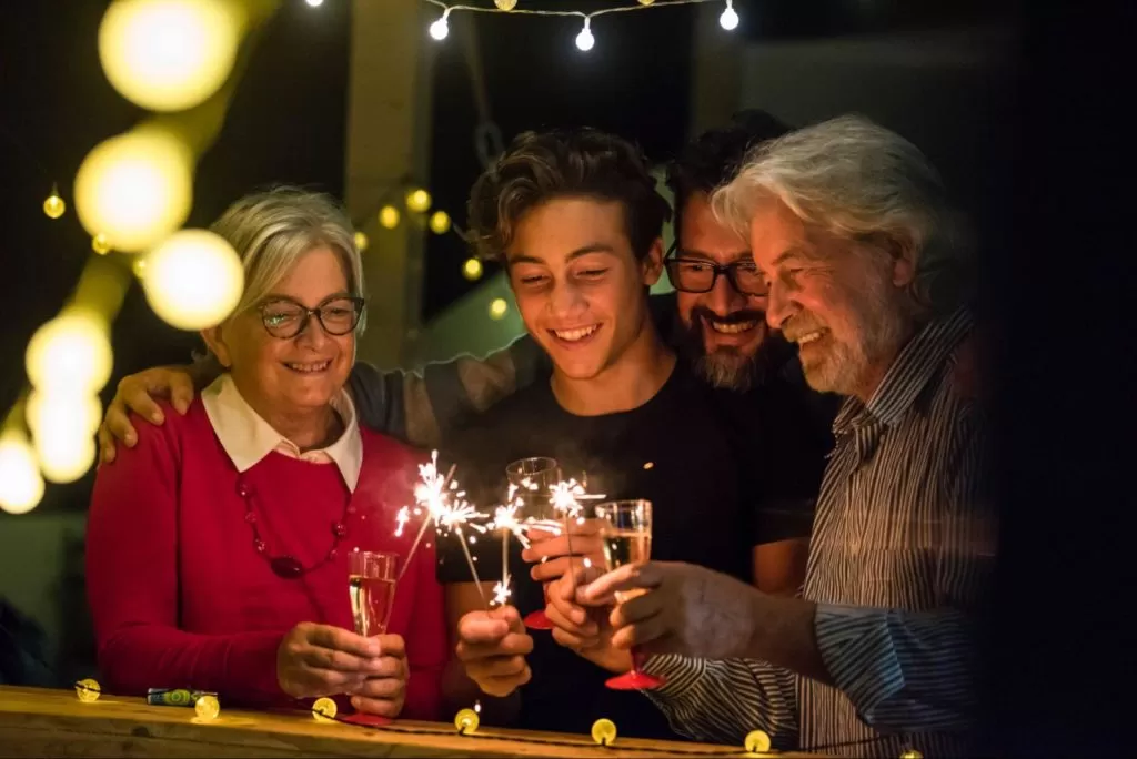 alt text: família reunida com velas que produzem faísca, comemorando o ano novo.