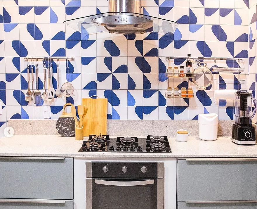 Cozinha Madesa Cinza com parede em azulejos azuis e brancos. Sobre a bancada clara, estão utensílios de uso diário.