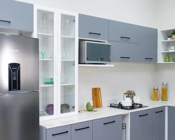 Cozinha com armários cinzas, cristaleira branca, geladeira de inox, micro-ondas e um cooktop instalado na bancada.