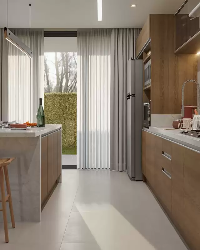 Cozinha com armários de madeira clara e branco, bancada de mármore, geladeira de inox, micro-ondas embutido, pia com torneira e cortinas brancas que cobrem uma grande janela. Há uma porta de vidro que leva ao jardim com árvores e arbustos ao fundo.