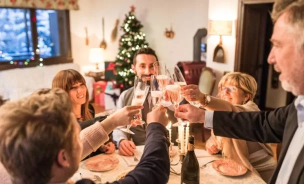 A imagem mostra pessoas reunidas à mesa celebrando uma ceia de ano novo simples e barata