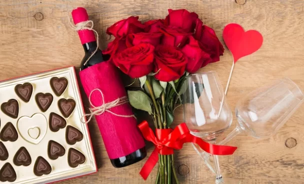 A imagem ilustra um buquê de rosas vermelhas, uma garrafa de vinho e uma caixa de chocolates como ideias para o dia dos namorados.