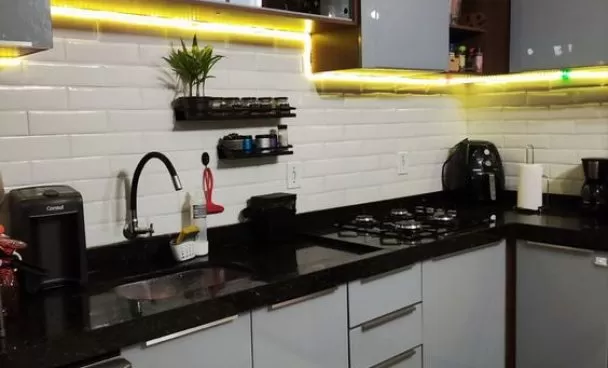uma cozinha cinza com iluminaçõ em led amarelo está em foco