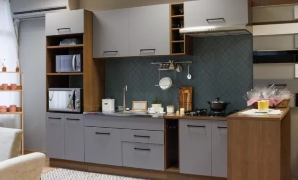 Cozinha com armários cinzas e detalhes em madeira. A bancada possui pia, fogão e utensílios de cozinha dispostos. No canto direito, há uma ilha de madeira, representando cozinha e copa integradas.